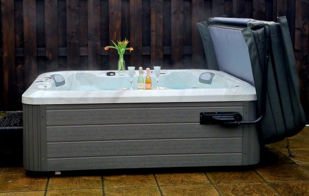 Hot tub with opened cover and a vase of flowers nearby.