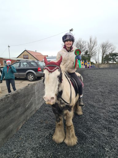 A rider on a horse in an outdoor arena, with onlookers nearby.